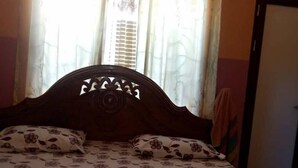 Un llit amb un mantell de llit estampat amb flors i un panell decoratiu al capçal.