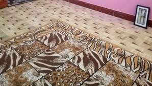 Una habitació amb una catifa estampada, parets roses i un quadre al mur.