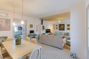 Cozy living space with a dining area, sofa, and TV, featuring a personal touch with framed pictures and a map.