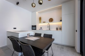 Una cocina moderna con una isla central, electrodomésticos integrados e iluminación colgante.