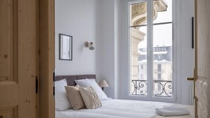 A bedroom with a large window, a bed with white bedding, and a wooden door. - Nice Apt With Balcony In Chamomix (Chamonix-Mont-Blanc)