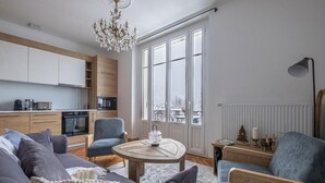 A modern living room with a sofa, armchairs, a round coffee table, and a chandelier. - Nice Apt With Balcony In Chamomix (Chamonix-Mont-Blanc)