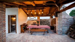 Enjoy al fresco dining in a traditional setting with a wooden bench and table, surrounded by exposed beams and a stone wall.