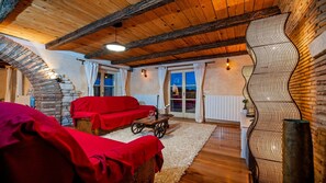 A cozy room with a stone fireplace, wooden beams, a red sofa, and a dining table. - Charming Villa Tomani with pool and jacuzzi (Krmed)