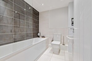 Une salle de bain moderne avec une grande baignoire, des toilettes et un lavabo.