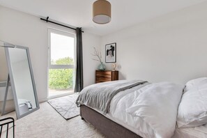 Une chambre à coucher avec un lit, un miroir, une commode, une fenêtre et une porte.