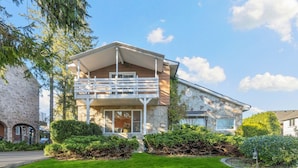 A two-story house with a stone facade, a balcony, and a well-maintained lawn.