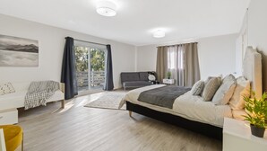 A modern bedroom with a large bed, a sofa, and a desk.