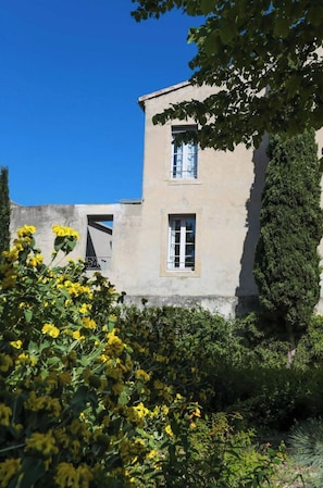 Um edifício com janela e porta, cercado por vegetação e flores.