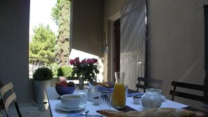 Une table de petit-déjeuner avec un bol de fruits, un verre de jus d’orange et une miche de pain.