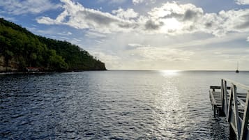 Un plan d’eau paisible, avec une jetée en bois qui s’avance sur l’eau, le tout entouré d’une colline boisée.