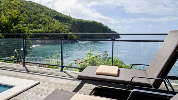A deck with lounge chairs and a pool, overlooking a coastal area with a forested hillside. - Les Galets Rouges Lodges & Spa (Bouillante)