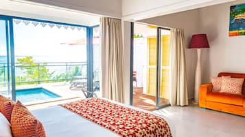 Habitación de hotel con cama, sofá, lámpara y vistas a una piscina y zona exterior.