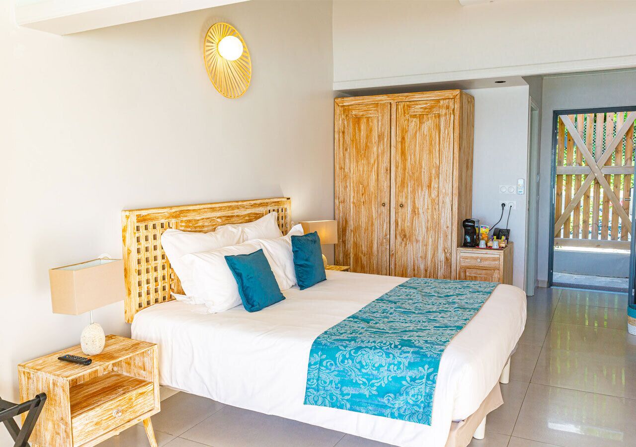 Ein Schlafzimmer mit einem großen Bett, einem Holz-Kopfteil und Blick ins Freie.