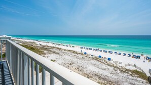 A beach view with a white railing, sandy beach, and turquoise water.