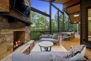 An outdoor patio with a stone fireplace, seating area, and dining setup. - Brookhaven - Hot tub & outdoor fire pit (Broken Bow)