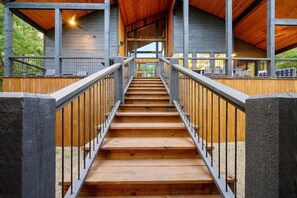 A wooden staircase with metal railings leading to an upper level of a building with a wooden ceiling.