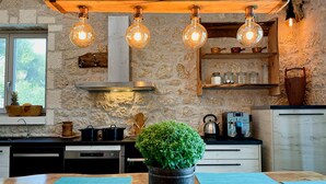 Une cuisine rustique avec des murs en pierre, des poutres en bois et des luminaires suspendus.