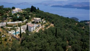 Une propriété située sur la côte, comprenant plusieurs bâtiments, une piscine et une végétation luxuriante.