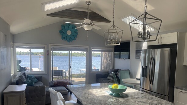 Una cocina moderna con una isla grande, un refrigerador de acero inoxidable y vista al agua.