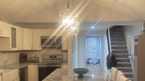 Una cocina moderna con una isla central, armarios blancos y una lámpara colgante.