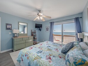 Une chambre à coucher avec un lit, une commode, un téléviseur et une vue sur l’océan.