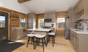 Cozinha moderna com ilha central, banquetas, detalhes em madeira e grandes janelas.
