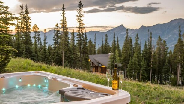 A hot tub with a mountain view, surrounded by trees and a cabin. - Derringer Haven | MTN Views, Hot Tub & Ski Access (Big Sky)