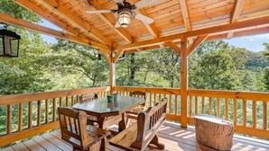 A wooden deck with a table and benches, overlooking a forested area. - Almost Heaven Cabin - River Access! (Murphy)