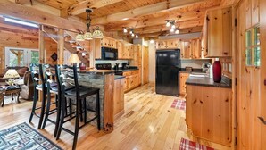 A wooden cabin interior with a kitchen, dining area, and a staircase. - Almost Heaven Cabin - River Access! (Murphy)