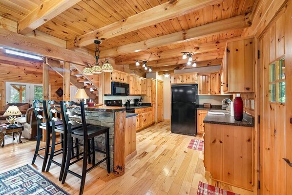 L’intérieur d’une cabane en bois comprend une cuisine, un coin repas et un escalier.