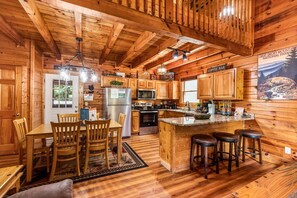 Ein Holzblockhaus-Interieur mit Küche, Essbereich und einer Bar.