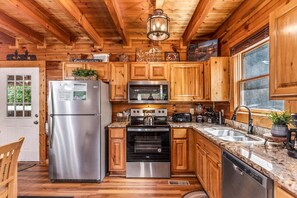Una cocina con armarios de madera, electrodomésticos de acero inoxidable y encimera de granito.