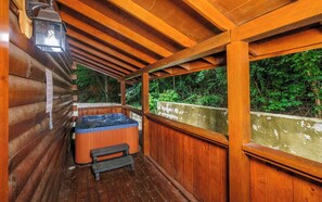 A wooden cabin with a hot tub and a lantern.