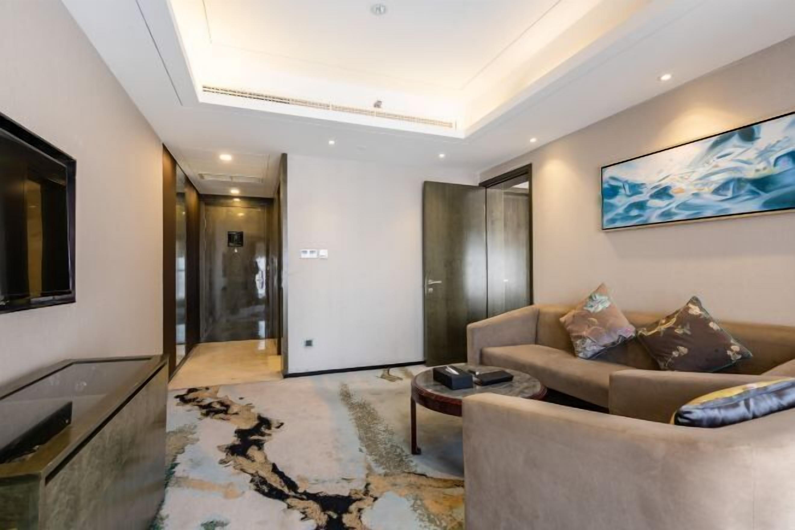 A modern living room with a sofa, coffee table, and a painting on the wall.