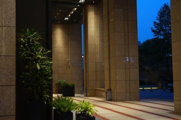 A building entrance with tiled walls, potted plants, and a visible door. - the Pearl Boutique Hotel (Yongjia)