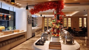 Un hall d’hôtel comprenant un comptoir d’accueil, une composition florale décorative et un espace salon.