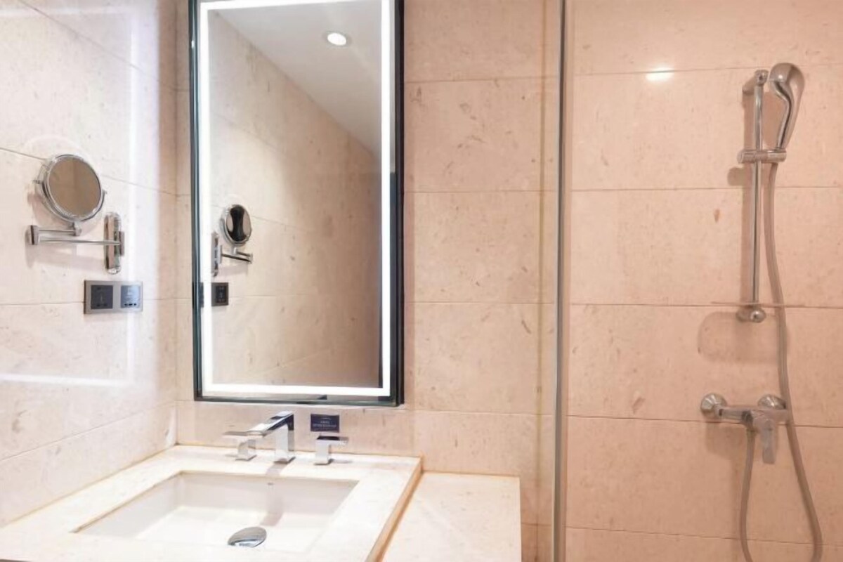 A bathroom with a large mirror, a sink, and a shower.