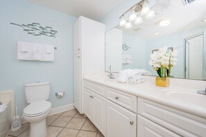 Bathroom features a white toilet, sink, and cabinet, along with a towel rack and decorative plant.