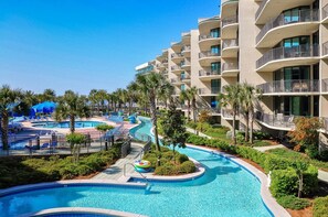 Relax by the resort's large, winding pool surrounded by lush greenery and palm trees.