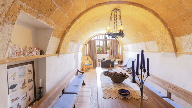 Une pièce accueillante, à l’architecture en arc, avec une table en bois, des bancs et une illustration encadrée représentant des animaux sauvages.
