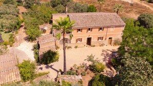 Un bâtiment traditionnel avec un toit en tuiles, entouré d’une végétation luxuriante et de palmiers.