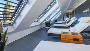 Un moderno salón en la azotea con tragaluces, sillones de descanso y una mesita de madera con un jarrón de cristal.