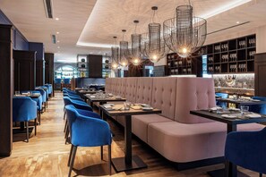 A restaurant interior with a bar area, seating arrangements, and a wine display. - Hotel Luc, Autograph Collection (Berlin)