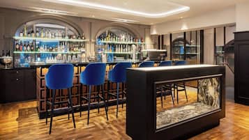 Un espace bar doté de plusieurs étagères remplies de bouteilles, de tabourets de bar et d’un comptoir central.