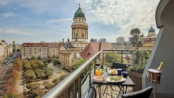A balcony with a table set for a meal, overlooking a cityscape with historic buildings and a prominent dome structure.