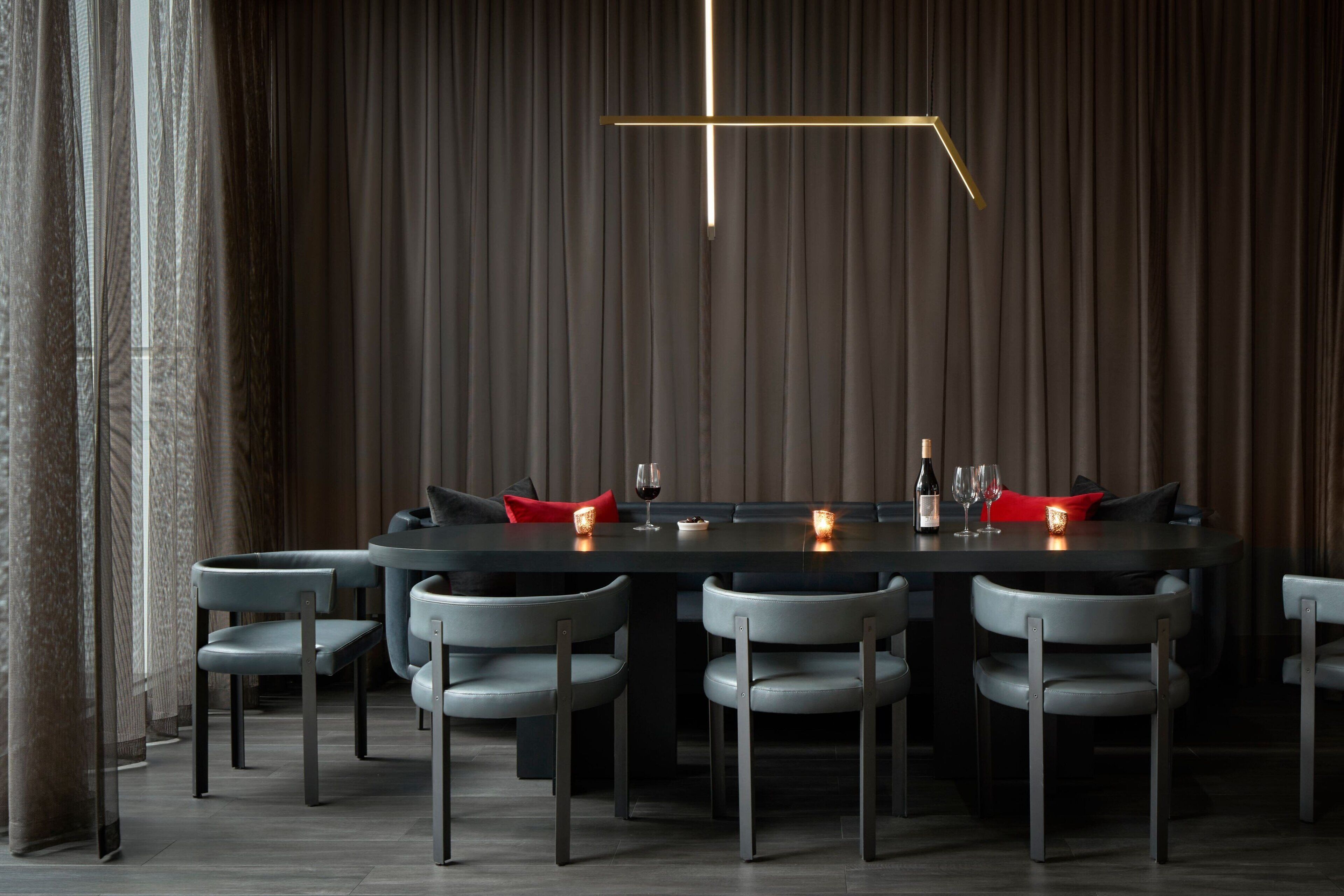 Un espace de salle à manger moderne avec une longue table, six chaises et des bougies.