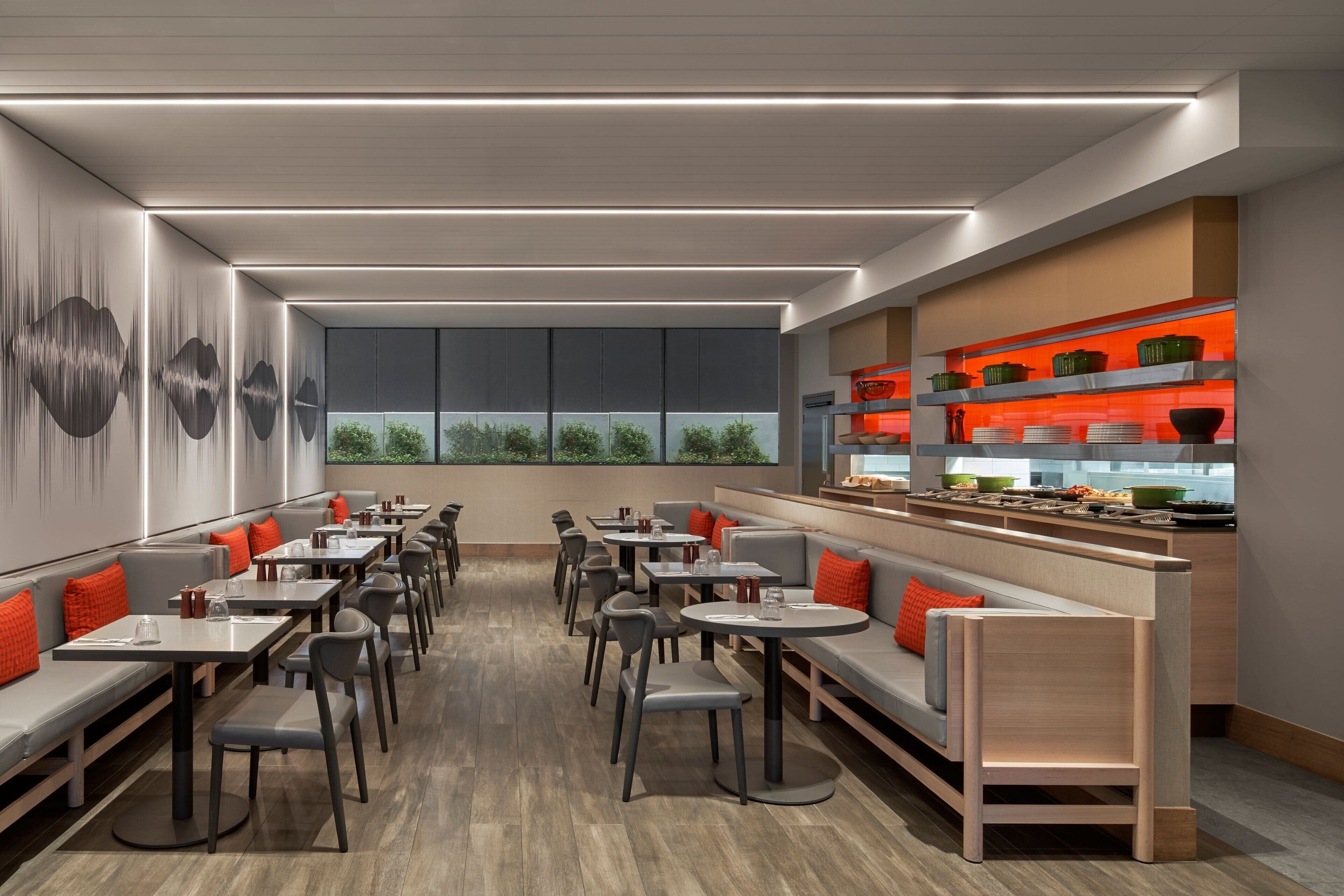Um restaurante moderno com um balcão extenso, diversas áreas de estar e uma cozinha visível ao fundo.