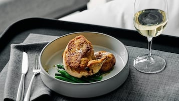 Ein Teller mit Essen und ein Glas Weißwein auf einem Tablett.