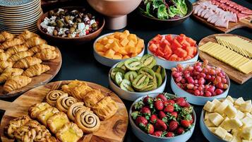 Diverses menes de menjar, com fruita, formatges i pastissos, disposats sobre una taula.